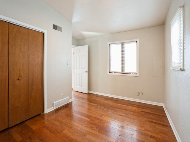 unfurnished bedroom featuring lofted ceiling, hardwood / wood-style flooring, and a closet