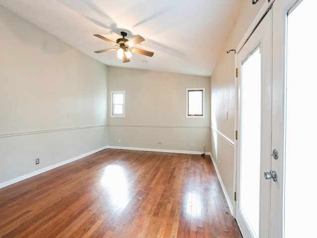 empty room with dark wood-type flooring, ceiling fan, and lofted ceiling