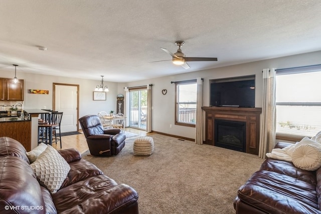 living room featuring light carpet, a textured ceiling, and ceiling fan with notable chandelier