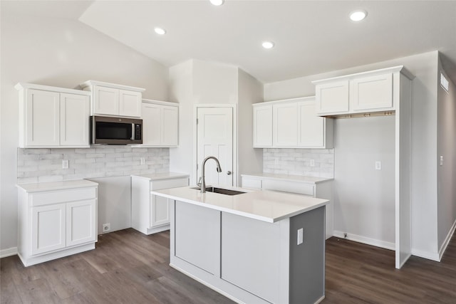 732 NE Deerfield Dr, Ankeny, IA 50021 - kitchen featuring stainless steel microwave, an island with sink, a sink, lofted ceiling, and decorative backsplash