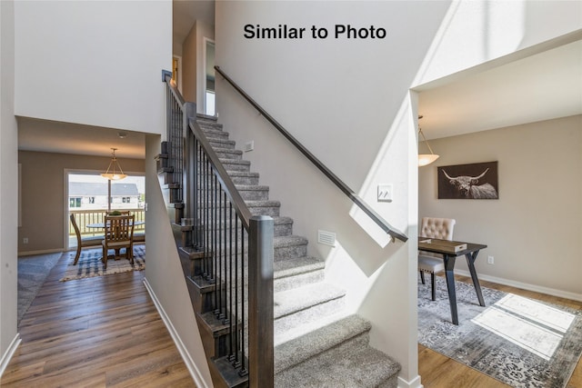 stairs with a towering ceiling and hardwood / wood-style flooring