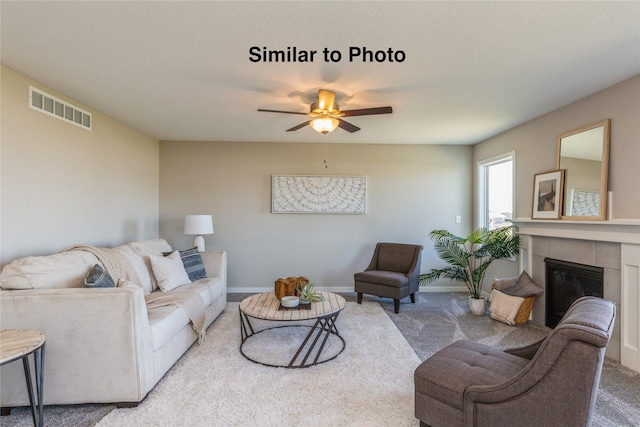 carpeted living room featuring ceiling fan and a fireplace