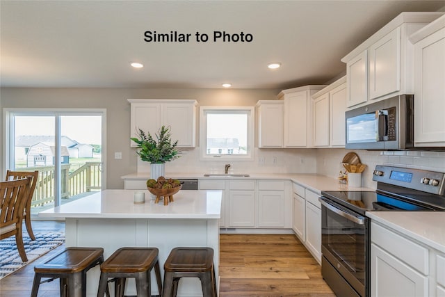 kitchen featuring decorative backsplash, sink, light hardwood / wood-style floors, and appliances with stainless steel finishes