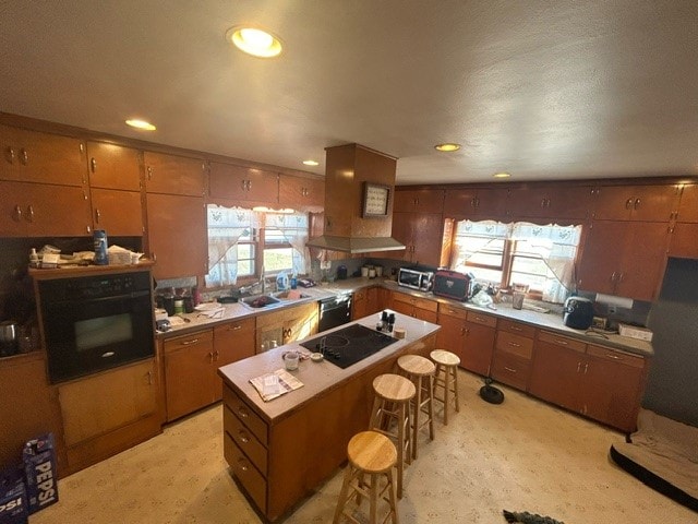 kitchen featuring a breakfast bar area, light carpet, sink, black appliances, and a center island