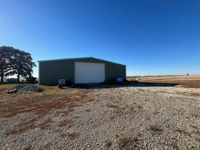 view of outdoor structure featuring a garage and a rural view