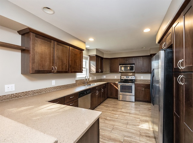 kitchen with sink, appliances with stainless steel finishes, light stone counters, and dark brown cabinets