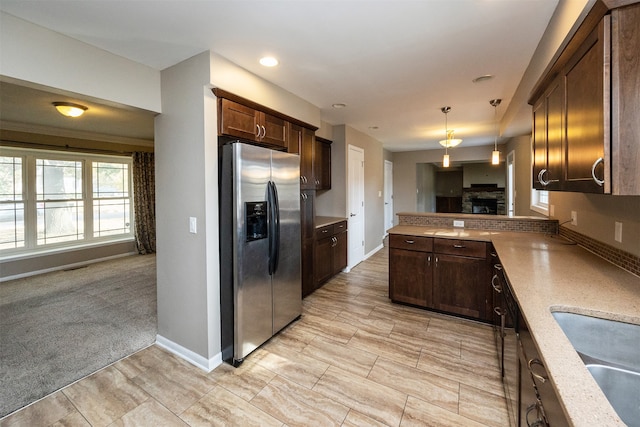 kitchen featuring sink, dark brown cabinetry, decorative light fixtures, light colored carpet, and stainless steel refrigerator with ice dispenser