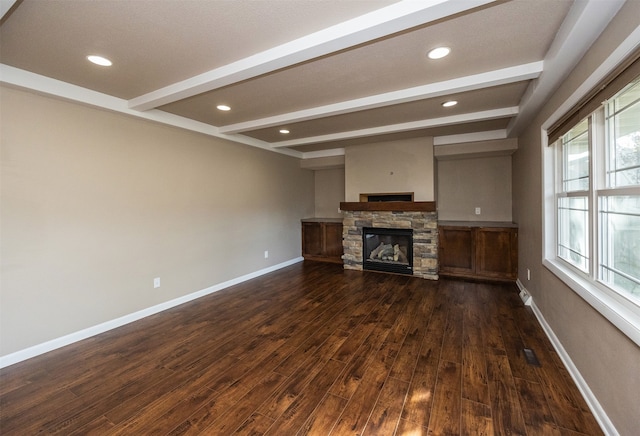 unfurnished living room with dark hardwood / wood-style floors, beamed ceiling, a fireplace, and a textured ceiling