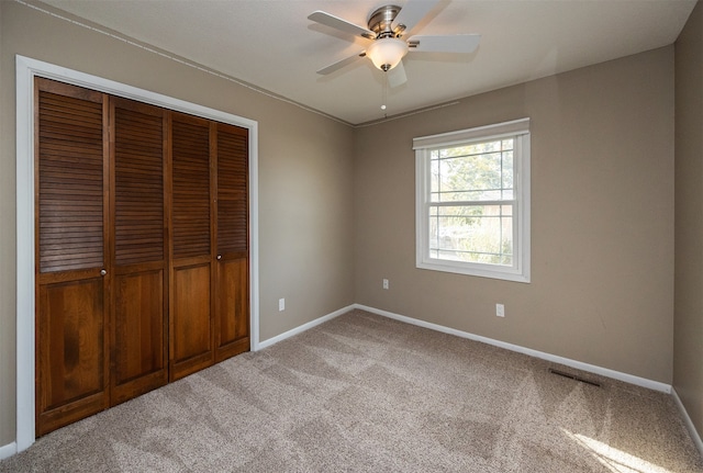 unfurnished bedroom with light carpet, a closet, and ceiling fan