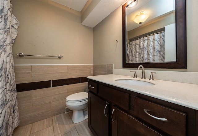 bathroom featuring toilet, vanity, and tile walls