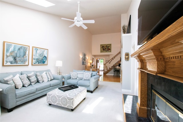 carpeted living room featuring ceiling fan, a towering ceiling, and a fireplace