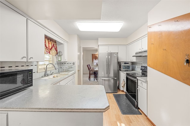 kitchen with black appliances, sink, backsplash, white cabinets, and light hardwood / wood-style flooring