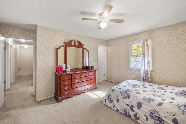 bedroom featuring light carpet, a textured ceiling, and ceiling fan