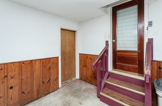 staircase with concrete floors and wood walls