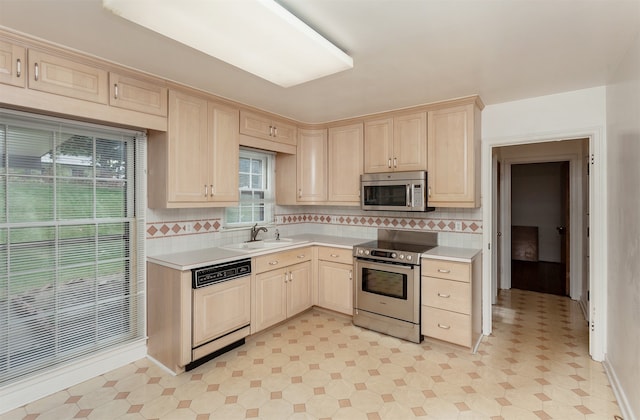 kitchen featuring appliances with stainless steel finishes, light brown cabinets, sink, and backsplash