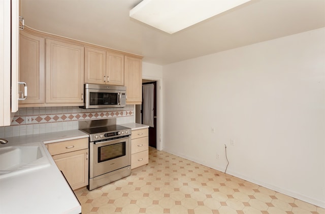 kitchen with backsplash, appliances with stainless steel finishes, and sink