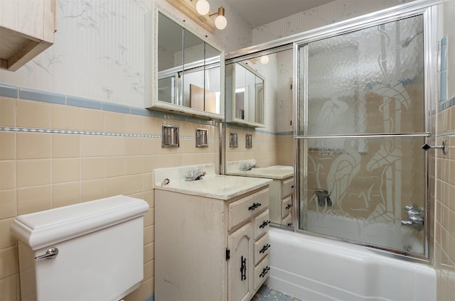 full bathroom with vanity, toilet, combined bath / shower with glass door, and tile walls