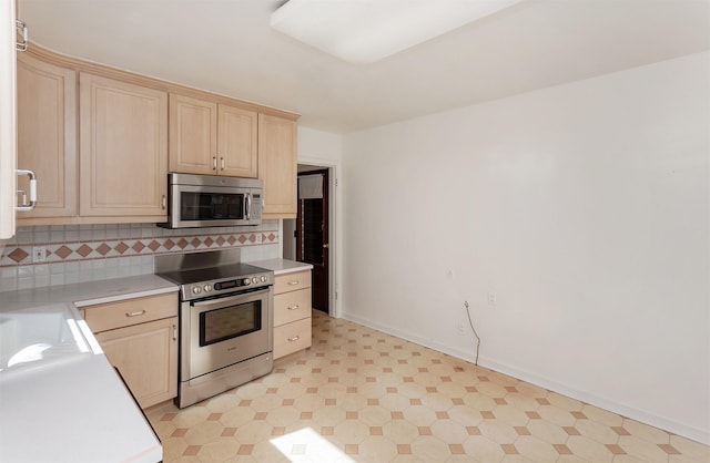 kitchen with tasteful backsplash, baseboards, light brown cabinetry, light countertops, and stainless steel appliances