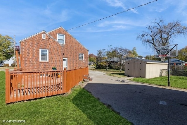 rear view of house with a lawn, a storage unit, and a wooden deck