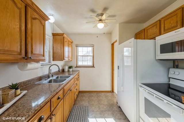 kitchen with white appliances, ceiling fan, dark stone countertops, and sink