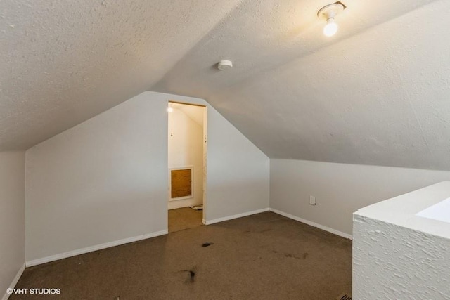 bonus room with a textured ceiling, dark carpet, and lofted ceiling