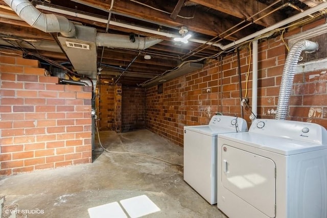 basement featuring separate washer and dryer and brick wall