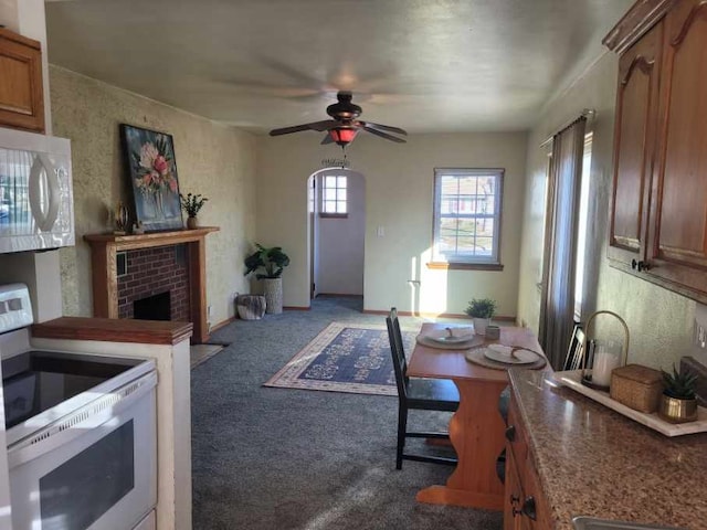 kitchen with a fireplace, electric range oven, ceiling fan, and light colored carpet