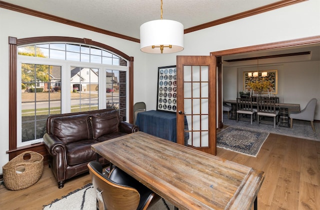 dining room with french doors, an inviting chandelier, crown molding, a textured ceiling, and light wood-type flooring