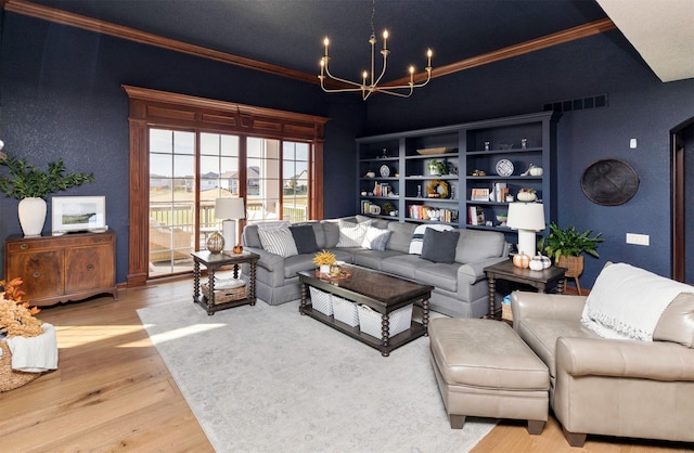 living room featuring a chandelier, light hardwood / wood-style flooring, built in features, and crown molding