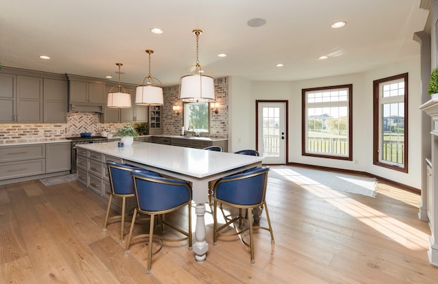 kitchen with a center island, sink, high end stainless steel range oven, decorative light fixtures, and decorative backsplash