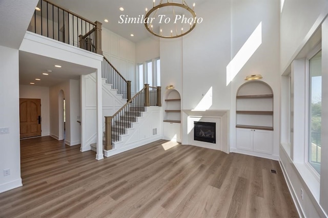 unfurnished living room with a healthy amount of sunlight, a high ceiling, and hardwood / wood-style floors