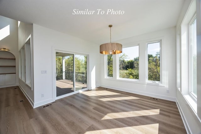 unfurnished dining area with wood-type flooring and a healthy amount of sunlight