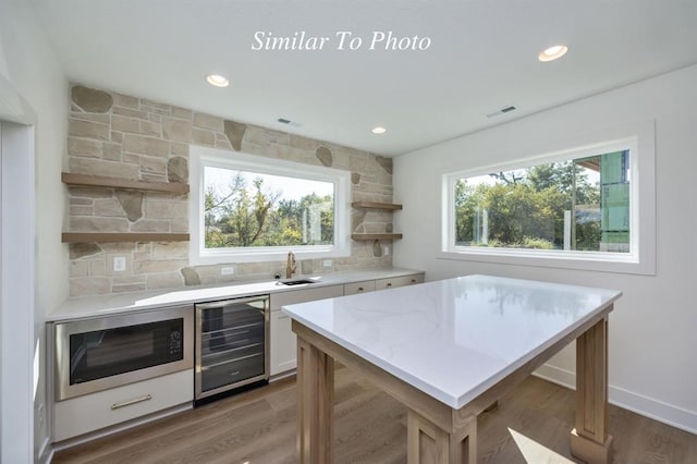 kitchen with wine cooler, hardwood / wood-style floors, stainless steel microwave, and plenty of natural light