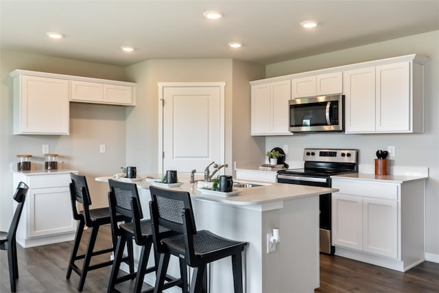 kitchen with sink, white cabinetry, an island with sink, stainless steel appliances, and dark hardwood / wood-style flooring