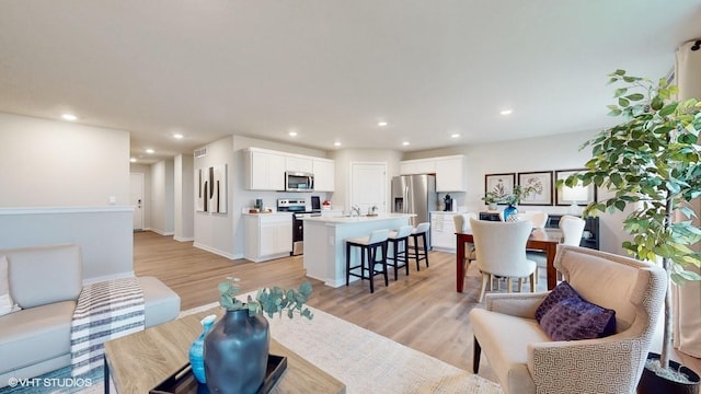 living room with recessed lighting, baseboards, light wood finished floors, and visible vents