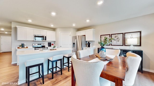 dining area with light wood-style floors, baseboards, and recessed lighting
