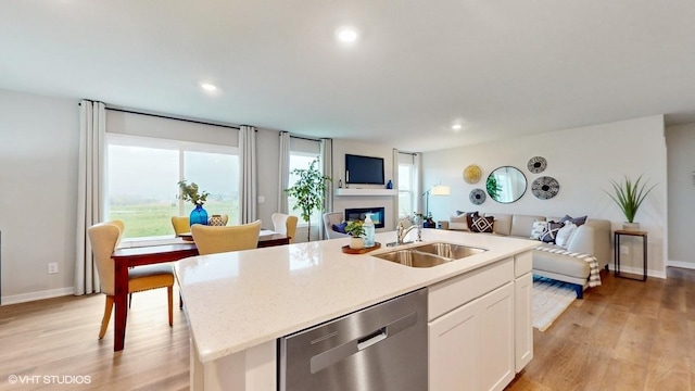 kitchen with a sink, a glass covered fireplace, dishwasher, and open floor plan