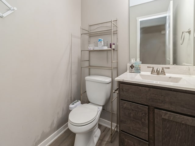 bathroom with toilet, hardwood / wood-style flooring, and vanity