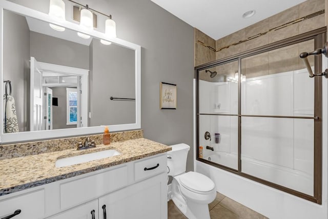 full bathroom featuring vanity, tile patterned flooring, shower / bath combination with glass door, and toilet