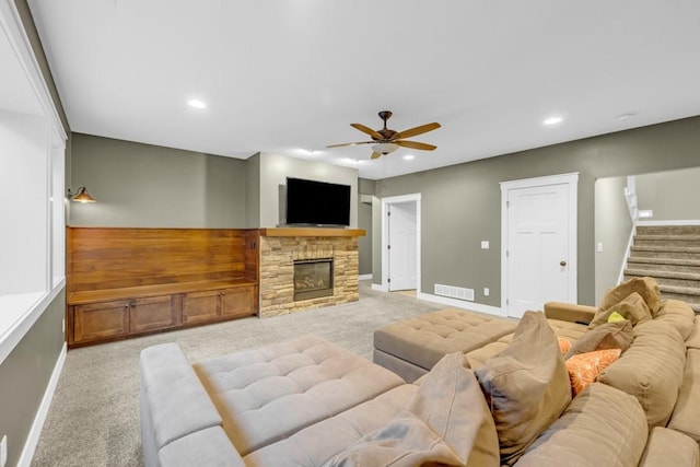 living room featuring ceiling fan, light colored carpet, and a fireplace