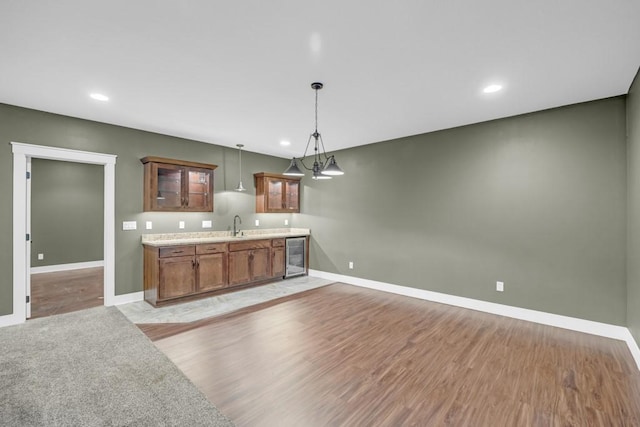 kitchen with sink, pendant lighting, beverage cooler, and light hardwood / wood-style floors