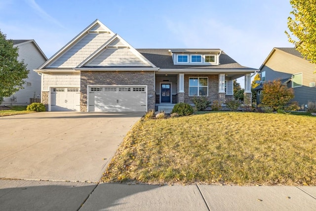 craftsman inspired home with a garage, a front lawn, and covered porch