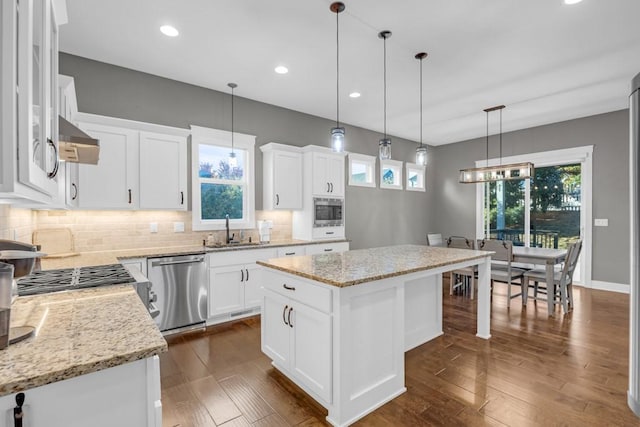 kitchen featuring sink, stainless steel appliances, light stone countertops, white cabinets, and a kitchen island