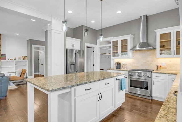 kitchen featuring wall chimney exhaust hood, white cabinetry, decorative light fixtures, high quality appliances, and a kitchen island