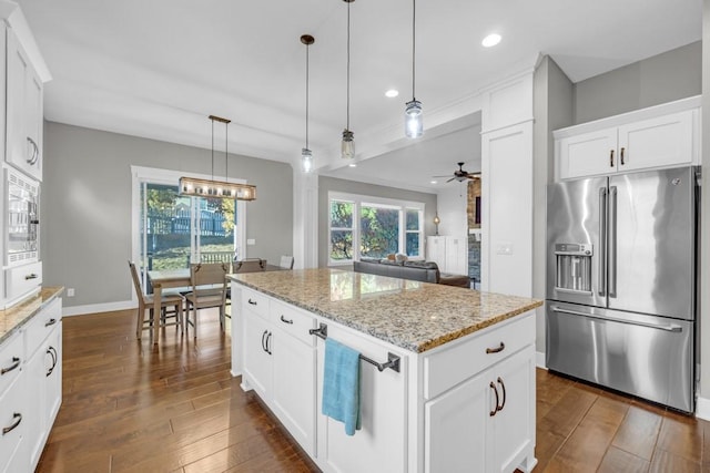 kitchen featuring white cabinetry, a center island, pendant lighting, stainless steel appliances, and light stone countertops