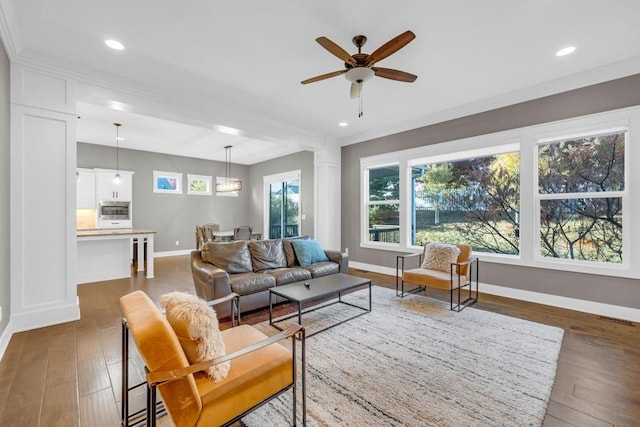 living room with crown molding, dark hardwood / wood-style floors, and ceiling fan