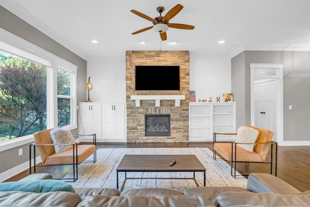 living room featuring ceiling fan, ornamental molding, a fireplace, and light hardwood / wood-style floors