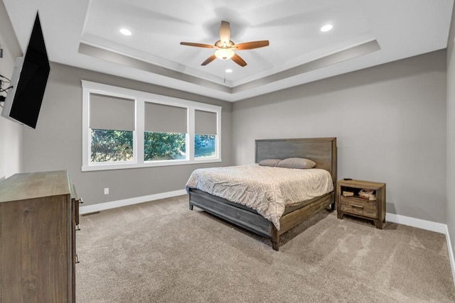 carpeted bedroom featuring ceiling fan and a tray ceiling