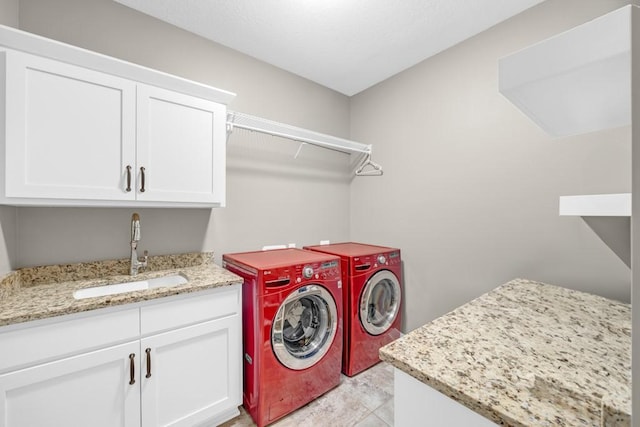 washroom with cabinets, washing machine and clothes dryer, and sink