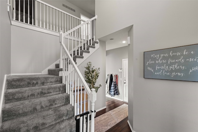 staircase featuring a high ceiling and hardwood / wood-style floors